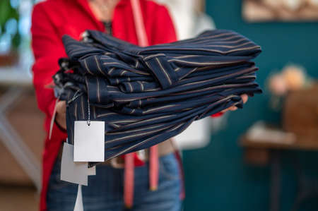 Hands holding out stack of clothes to cameraの写真素材