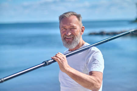 Man with paddle on shoulder looking at camera