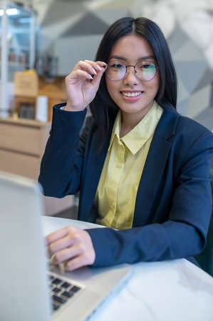 Woman sitting at laptop looking at cameraの写真素材