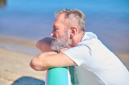 Profile of pensive man resting on seashoreの写真素材