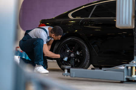 Auto repair worker checking the wheel of the carの写真素材