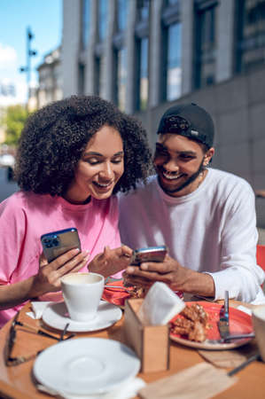 Two young people watching something on the phone and smilingの写真素材