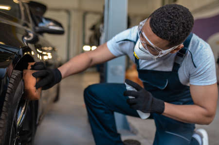 Auto detailer buffing the car wheel with glossの写真素材