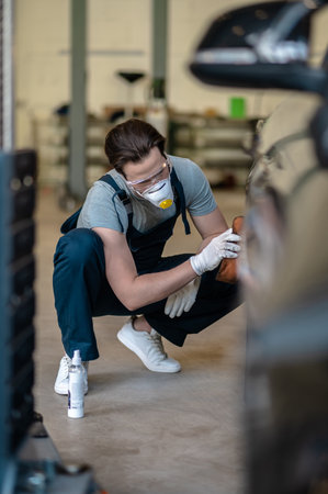 Professional mechanic in the respirator buffing the customer carの写真素材