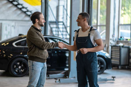 Joyful mechanic greeting his customer at the service stationの写真素材
