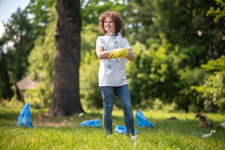 Curly-haired young volunteer gethering plastic bottles