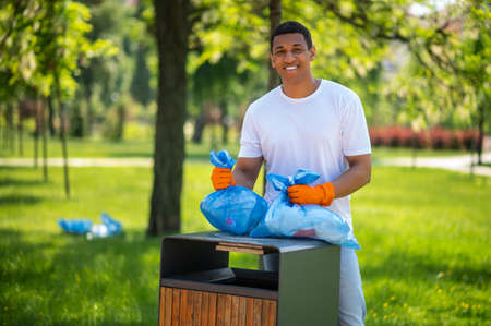 Man standing near trash can smiling at cameraの写真素材