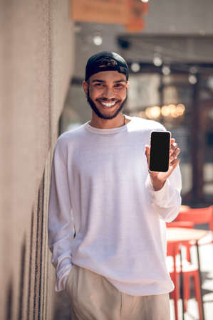 Handsome man in a black cap with a smartphone in the street