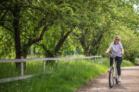 A mid aged woman riding a bike in a parkの写真素材