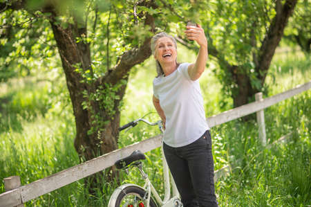 A woman with a bike making selfie and smilingの写真素材