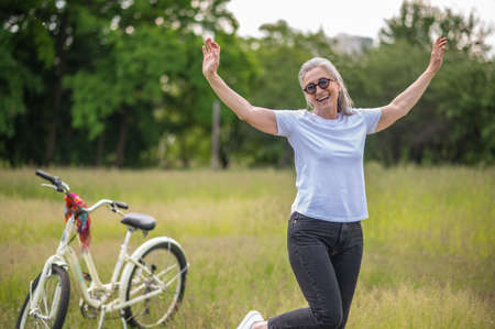 A cheerful woman in eyeglasses with a bike in the parkの写真素材