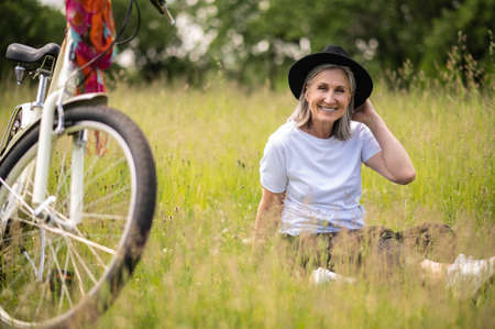 A happy woman with a black hat enjoying and having fun in the countrysideの写真素材