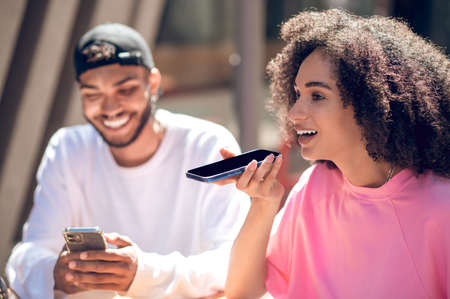 Cute smiling couple, a woman recording a voice messageの写真素材