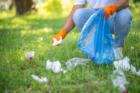 Man crouched picking up trash in parkの写真素材