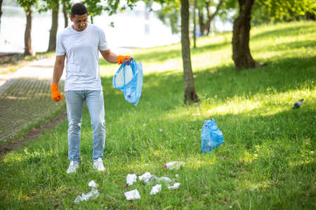 Man standing looking at garbage on grass