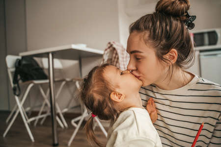 Affectionate mother kissing her cute little daughter on the lipsの写真素材