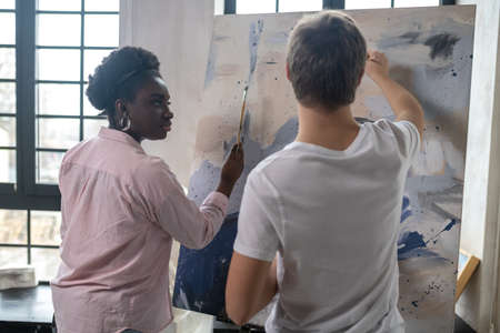 A tutor and a student near the easel looking positiveの写真素材