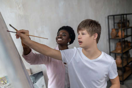 A tutor and a student near the easel looking positiveの写真素材