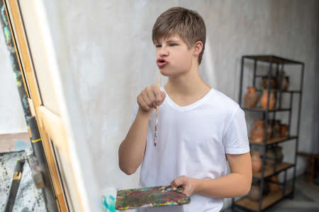 A boy near the easel looking thoughtful and concentratedの写真素材