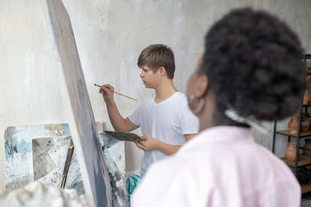 A positive tutor having a workshop with a boy with down syndromeの写真素材