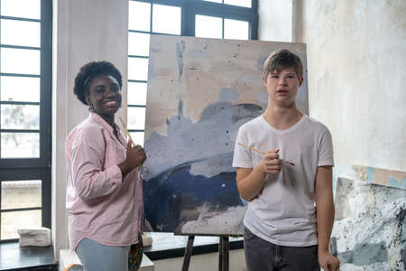 A tutor and a student near the easel looking positiveの写真素材