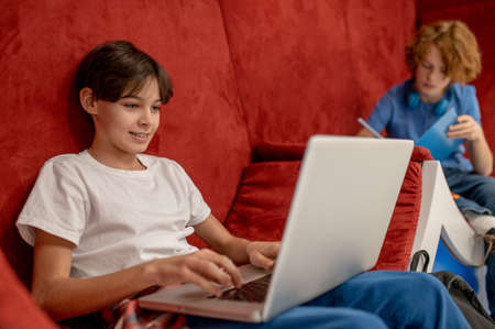Two school boys feeling comfortable in the lounge zone and doing homework