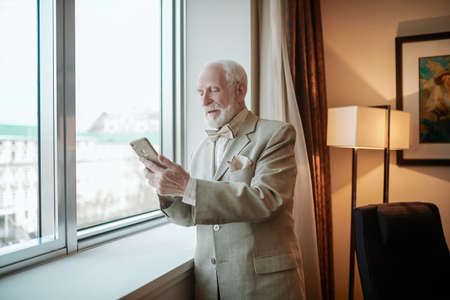 Elegant man in a suit looking at the smartphone with anticipationの写真素材