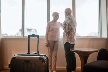 Senior couple standing near the window and looking happyの写真素材