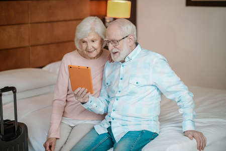 Senior man and woman watching something online and looking excitedの写真素材