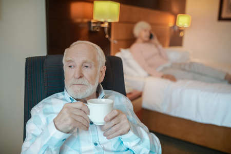 Senior bearded man having his morning coffee and looking thoughtful