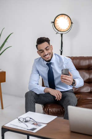 Confident man smiling looking at smartphone