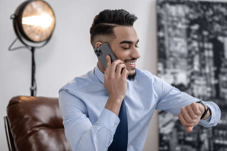 Man talking on smartphone looking at wrist watch