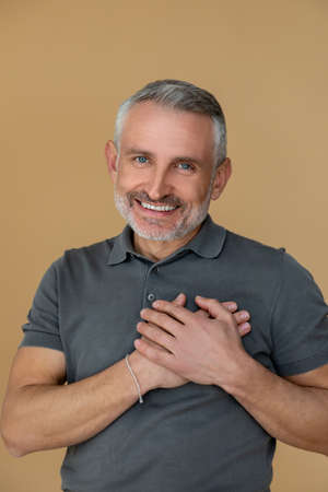 Nicely smiling man putting his hands on his heart