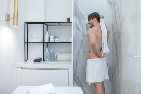 Well-built young man drying himself with a towel after showerの写真素材