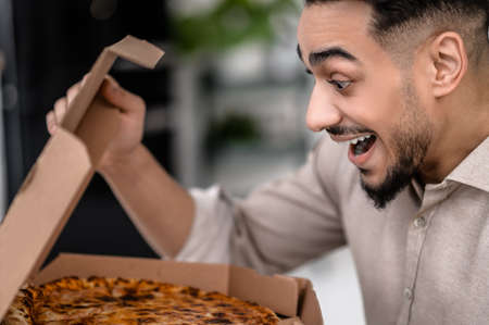 Man sideways to camera looks enthusiastically at pizzaの写真素材
