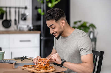 Man touching pizza sitting sideways to cameraの写真素材