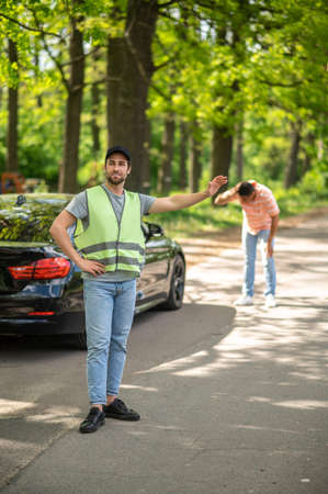 Serviceman in a yellow vest hitchhiking on the roadの写真素材