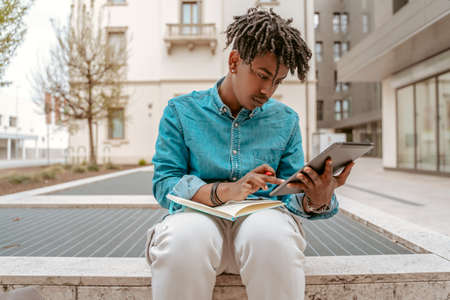 Guy sitting looking at tablet touching screenの写真素材