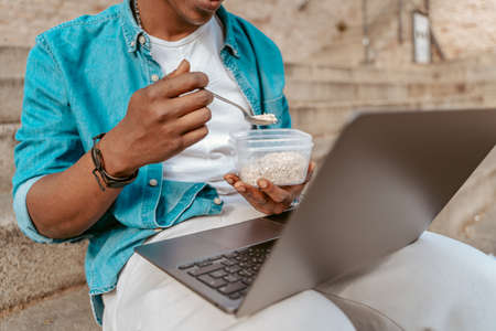 Guy eating in front of laptop outdoors