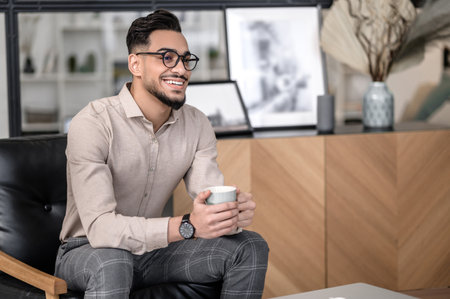 Successful man with coffee sitting smilingの写真素材