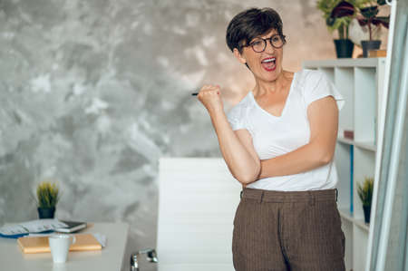 Mature dark-haired woman standing near the flipchart and working on project detailsの写真素材