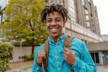 Guy smiling at camera standing on city streetの写真素材