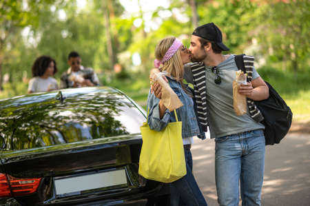 Young couple holding sandwiches and kissingの写真素材
