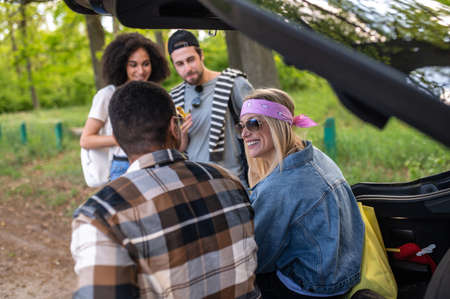 Group of young people sitting near the acr and talkingの写真素材