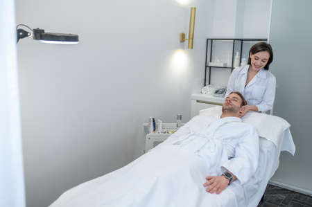 Dark-haired professional doing face massage to a male customer