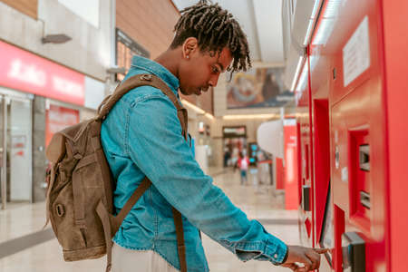 Guy standing sideways to camera near self-service terminalの写真素材
