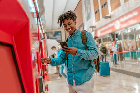 Guy smiling in smartphone touching self-service terminal