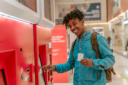Guy smiling at camera standing near ticket terminalの写真素材