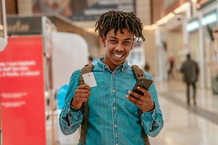 Happy guy showing ticket to camera standing at stationの写真素材