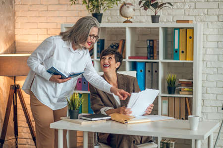 Two businesswomen discussing project details and looking involvedの写真素材